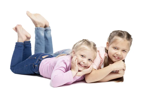 Le amiche in maglioni rosa stanno mentendo e sorridendo. Bambini piccoli. isolato su sfondo bianco . — Foto Stock