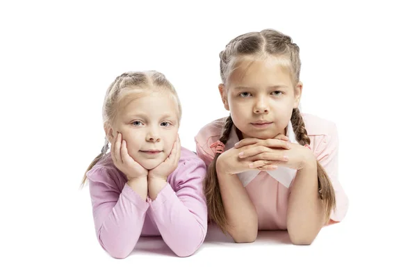 Vriendinnen in roze truien liggen en glimlachen. Kleine kinderen. Geïsoleerd over witte achtergrond. — Stockfoto