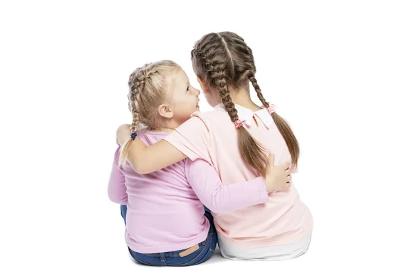 Девушки в розовых свитерах и джинсах обнимаются и смеются. Вид сзади. Изолированный на белом фоне . — стоковое фото