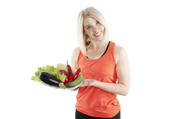 Smiling young woman holding a plate with vegetables. Vegetarianism and raw food diet. Health and proper nutrition. Isolated over white background. — Stock Photo, Image