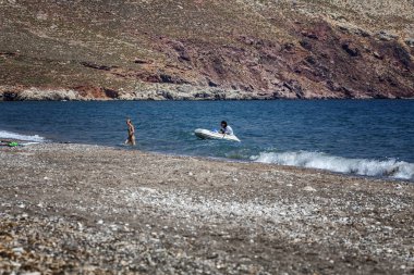 Tilos, Yunanistan, 07.22.2015: İnsanlar şişme bota biniyor. Güneşli bir günde dağlarda güzel koy. 