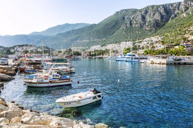 Kaş, Türkiye, 05.16.2019: Parlak güneşli bir günde güzel bir şehir yat limanında turist gemileri ve küçük tekneler. Muhteşem bir kartpostal manzara.