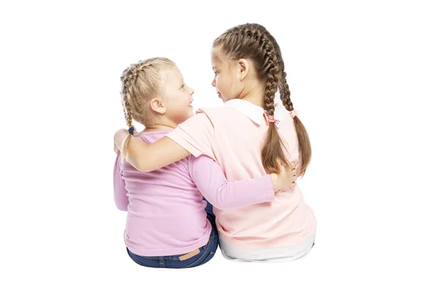 Małe dziewczynki dziewczyny w dżinsy i różowe swetry siedzą i przytulanie. Izolowane na białym tle. — Zdjęcie stockowe