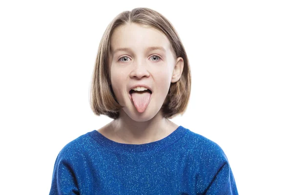 Roztomilá dívka v modrém svetru ukazuje jazyk. Izolované bílé pozadí. — Stock fotografie