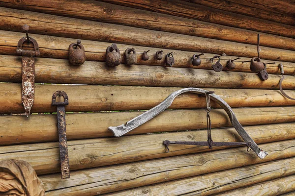 Rustikale schmiedeeiserne Utensilien an der Wand eines Holzblockhauses. — Stockfoto