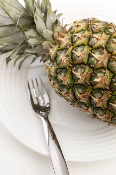 Całość ananasa na talerzu na białym tle. Smaczne i zdrowe wegetariańskie jedzenie. — Zdjęcie stockowe