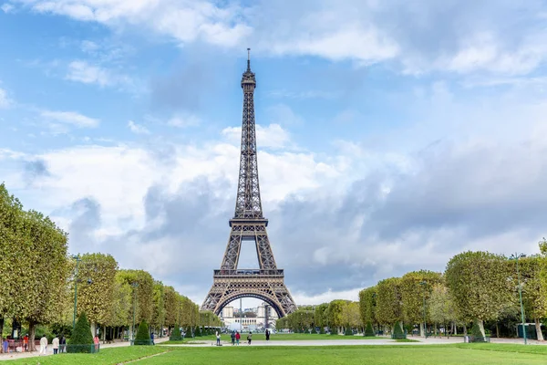 Blick auf den Eiffelturm von einem herbstlichen Park vor blauem Himmel. Spaziergänger werden fotografiert. — Stockfoto