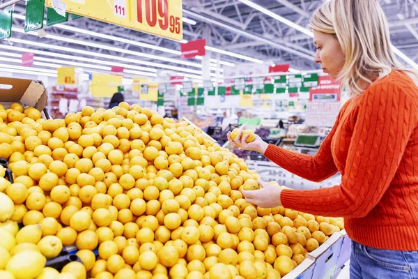 Laranjas amarelas suculentas em um balcão em um supermercado. Jovem escolhe frutas . — Fotografia de Stock