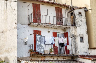 Pencerelerinde kuru giysiler olan eski beyaz bir ev. Yakın plan..