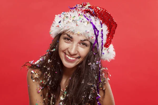Красивая молодая женщина в шляпе Санты Клауса улыбается. Рождественская сказка Открытка. Красный фон . — стоковое фото