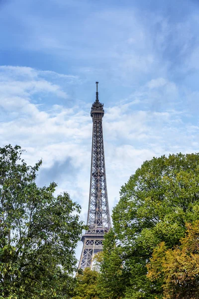 Torre Eiffel no verde das árvores contra o céu azul em um dia ensolarado brilhante . — Fotografia de Stock