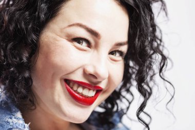 Güzel, genç, gülen bir kadın. Güzel dişleri olan kıvırcık esmer. Yakın plan. Beyaz arkaplan.