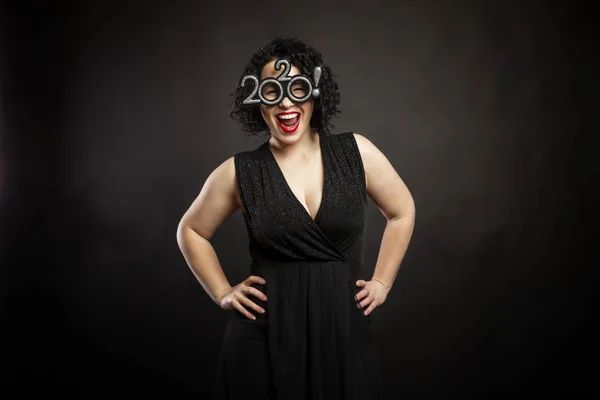 Belle jeune femme rieuse dans des lunettes de nouvelle année. Brune bouclée. Fond noir . — Photo