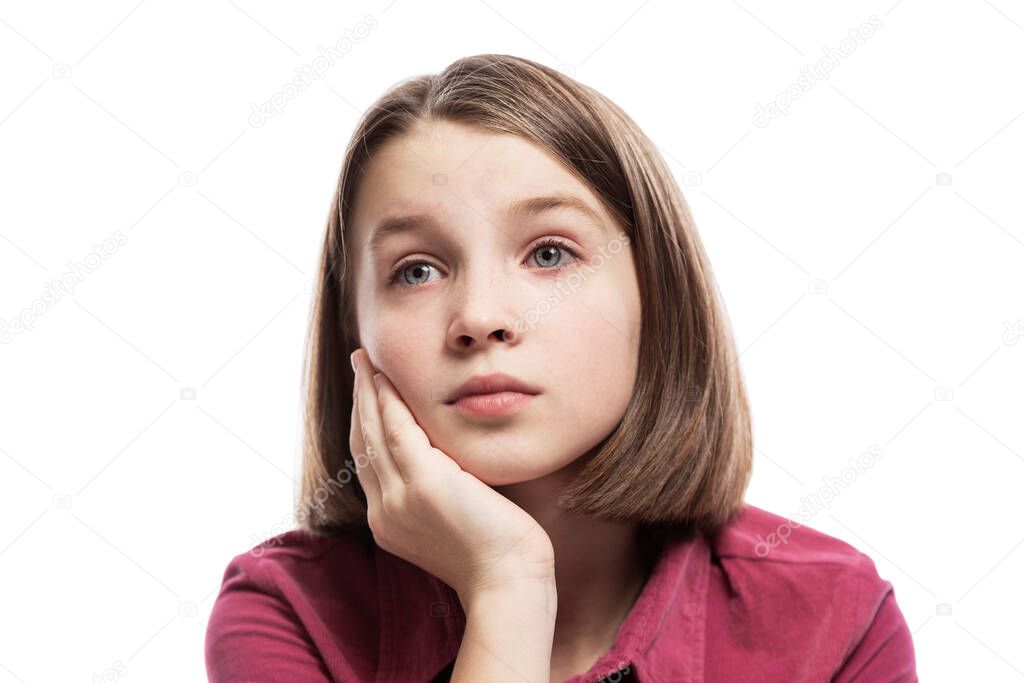 Pensive teenage girl sitting propping her head on her hand. Close-up. Isolated on a white background.