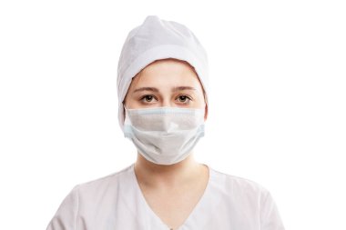 Beyaz paltolu, şapkalı ve maskeli genç bir doktor. Koronavirüs salgını sırasında alınan önlemler. Beyaz bir arka planda izole edilmiş. Yakın plan..