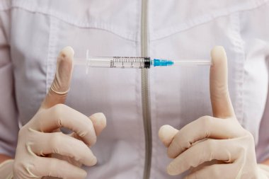 Eldivenli bir doktor şırınga tutuyor. Koronavirüs salgını sırasında insanlığın aşılanması ve aşılanması. Yakın plan..