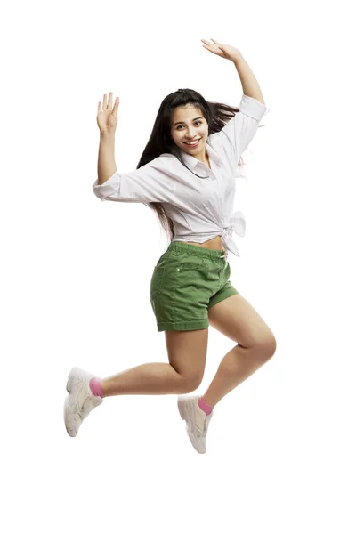 穿着白衬衫和绿短裤笑着的小女孩跳了起来 留长发的布鲁内特被白色的背景隔离了垂直方向 — 图库照片