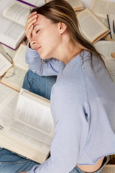 Una Giovane Ragazza Stanca Siede Tra Una Grande Pila Libri — Foto Stock