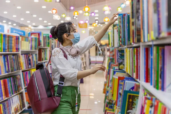 Egy Fiatal Lány Orvosi Maszkban Könyvet Választ Egy Könyvesboltban Tudás — Stock Fotó