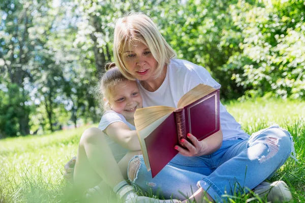 Jonge Vrouw Met Een Dochter Leest Een Boek Een Park — Stockfoto