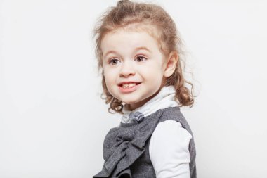 Beyaz arka planda kıvırcık saçlı, gülen küçük bir kız. Yakın plan..