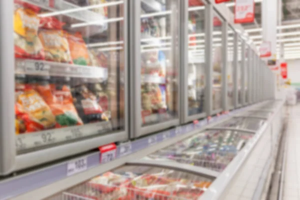 Frozen food in a refrigerator in a large supermarket. Blurred. Side view.