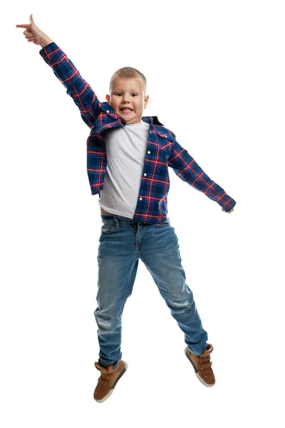 その少年はジャンプしている ジーンズとシャツを着た太った小学生 エネルギーと動きだ 白い背景に隔離されている — ストック写真