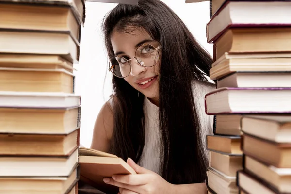 本がたくさんある若い女の子がテーブルに座っている 眼鏡をかけたブルネットの笑顔 学校に戻る 知識と教育 — ストック写真
