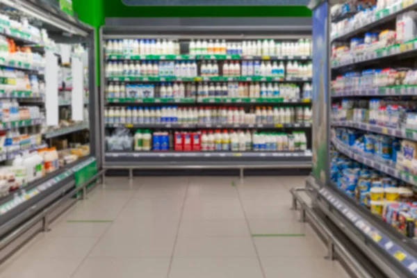 Shelves with dairy products in the supermarket. Big choice. Blurred.