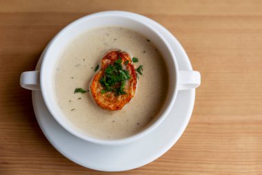 Kremalı çorba, beyaz bir tabakta, ahşap bir masada. Üst Manzara. Metin için boşluk.