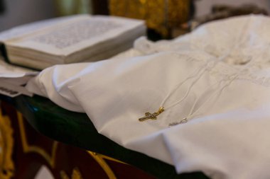 Tapınağında haç olan beyaz vaftiz gömleği. Geleneksel vaftiz töreninde yemek pişirmek. Yakın plan..