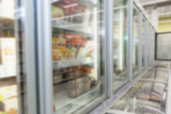 Glass cabinets with refrigerated food in the supermarket. Side view. Blurred.