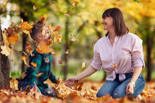 Mom and son are resting in a beautiful colorful autumn park. Love and tenderness. Soft focus.
