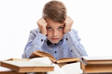 Okul çocuğu masada kitaplarla sıkılıyor. Eğitim ve eğitim. Beyaz arkaplan.