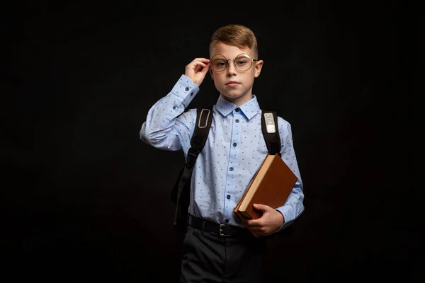 眼鏡をかけ リュックと本を手にした少年 黒の背景 — ストック写真
