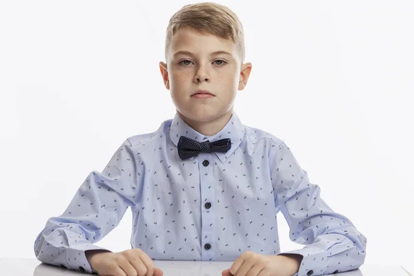 Serious Schoolboy Blue Shirt Bow Tie Sits Table White Background — Stock Photo, Image