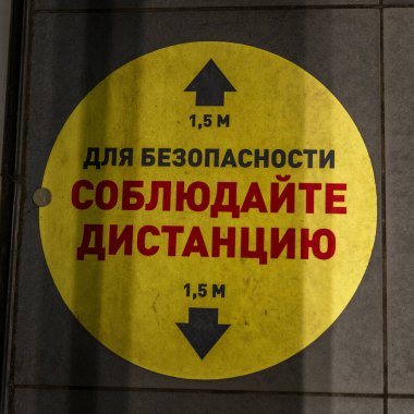 Mağazanın zemininde 1,5 metrelik mesafeyi korumakla ilgili sarı etiket var. Moskova, Rusya, 15 / 05 / 2020.