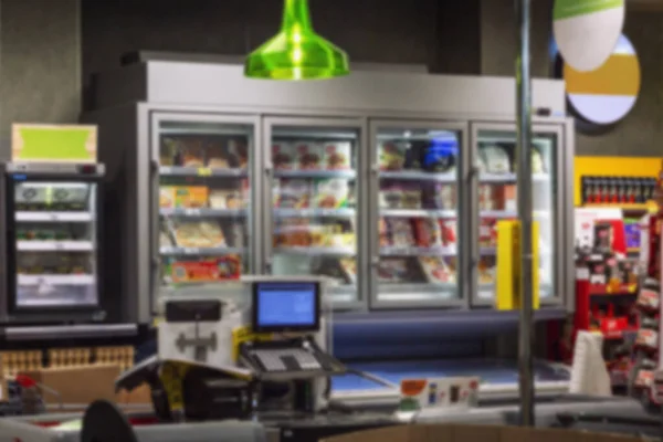 Grocery store interior. Showcase with frozen products and cash register. Blurred.