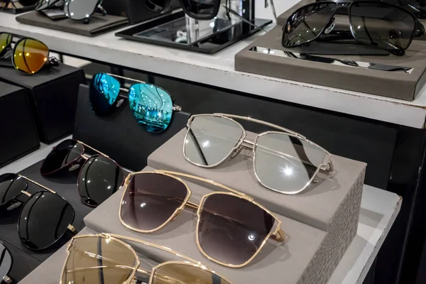 Various of colorful sun glasses in the shop display shelves. Selective focus