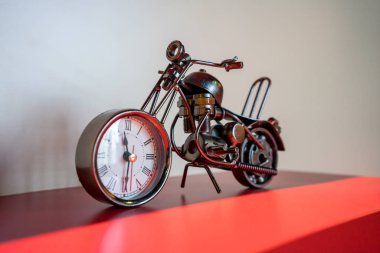 Ev dekorasyon için kırmızı rafındaki beyaz saatli metal motosiklet.
