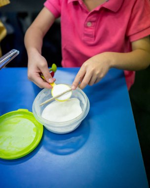 Çocuk el scooping ve bilimsel deney için kaşık ölçme içinde beyaz toz seviyeye bir çubuk kullanarak. Ev okul tasarım.