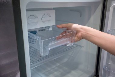 Kadın eli açık şeffaf plastik buz konteyner çekmece yeni bir buzdolabı.