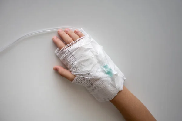 Kid hand with an elastic bandage  with the tube of normal saline infusion. Concept first medical aid.