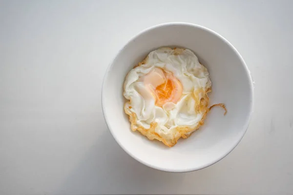 Closed up beautiful fried egg in white bowl isolated on white background. Safety food served for patient in the hospital.