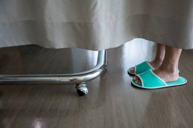 Hastanede perdenin arkasındaki yeşil terlik giyen bir kişinin ayak closeup düşük bölümü