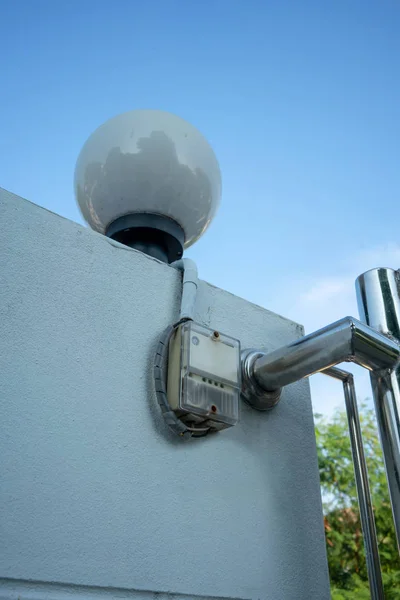 Auto On-Off street light switch installed on concrete wall near stainless sliding door.