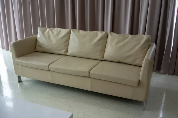 白色地板上的新白色皮革沙发对浅褐色织物窗帘 — 图库照片