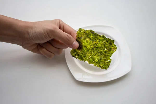 Mano Recogiendo Hoja Algas Fritas Coreanas Sobre Plato Blanco Sobre — Foto de Stock