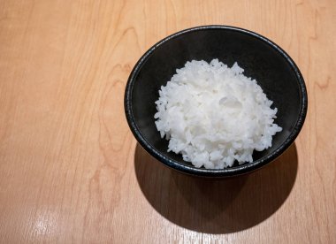 Ahşap masa arka plan üzerinde siyah seramik kase Japon pirinç