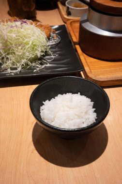 Ahşap masa arka plan üzerinde siyah seramik kase Japon pirinç